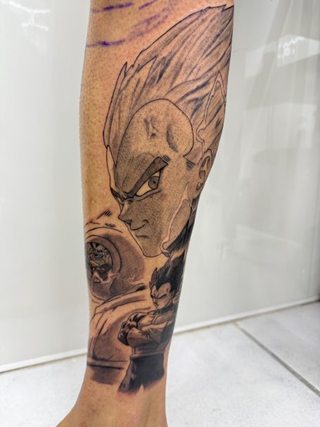 Tatoeage van een personage met een krachtige uitstraling op een onderbeen.