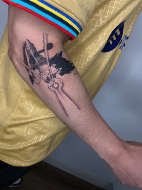 Tattoo op een arm met een ontwerp van een anime-figuur en abstracte elementen.